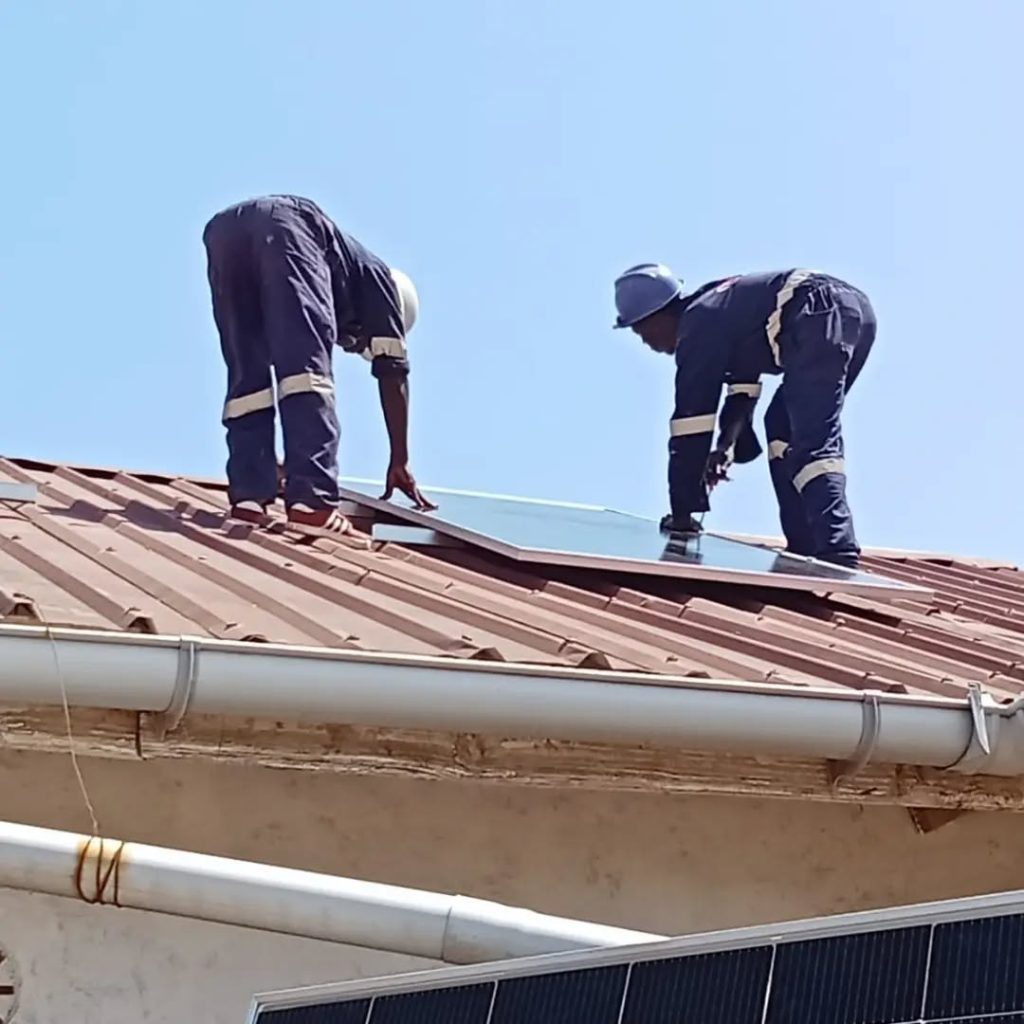 Technicians securing a solar panel to the rooftop mounting rails